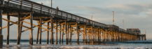 Wooden pier extending over the ocean at sunset